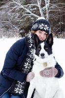 retrato de mulher jovem e bonita com seu cachorro preto e branco em um fundo de floresta de coníferas de inverno. foto