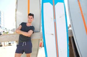 jovem, sorrindo e em pé com prancha de surf na praia