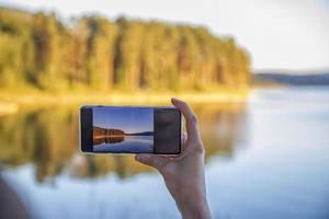 mão de mulher segurando smartphone tirando foto da bela natureza. fotografia de telefone móvel e conceito de vídeo