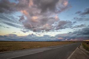 incrível pôr do sol sobre a estrada e campo depois da chuva foto