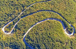 vista aérea de curvas de estrada incríveis na montanha da floresta vista panorâmica da estrada de curva acentuada por drone foto