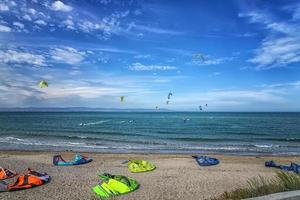 kitesurfistas surfando o vento nas ondas em um dia ensolarado de verão foto