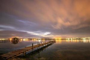 belas reflexões noturnas no mar do porto e nuvens em movimento foto