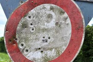 close-up detalhado de buracos de bala de tiros em um sinal de trânsito foto