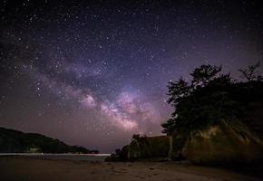 Via Láctea acima da noite estrelada do oceano foto