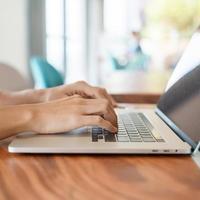 mulher usando laptop, mulher freelance digitando notebook de computador de teclado no café ou escritório moderno. tecnologia, digital online e conceito de rede foto