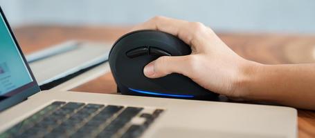 mão de mulher usando mouse ergonômico de computador, prevenção de dor no pulso porque trabalha muito tempo. tenossinovite de Quervain, sintoma de interseção, síndrome do túnel do carpo ou conceito de síndrome do escritório foto