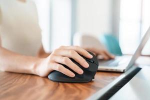 mão de mulher usando mouse ergonômico de computador, prevenção de dor no pulso porque trabalha muito tempo. tenossinovite de Quervain, sintoma de interseção, síndrome do túnel do carpo ou conceito de síndrome do escritório foto