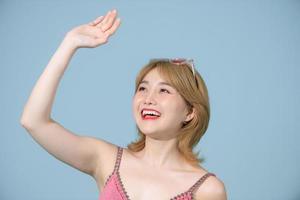 linda mulher asiática em pé no estúdio e levantando a mão para cobrir o rosto da luz solar. foto