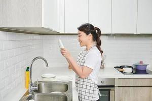olha que limpo. mulher bonita em pé na cozinha e mostrando os resultados de seu trabalho foto