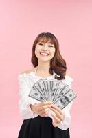 imagem de mulher encantada vestindo roupas básicas sorrindo e segurando dinheiro isolado sobre fundo rosa foto
