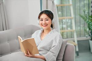 retrato bela jovem mulher asiática ler livro no sofá no interior da sala de estar foto