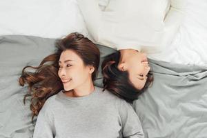 duas mulheres sorridentes deitam na cama foto