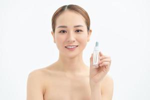 bela jovem asiática mostrando produto de cuidados com a pele isolado no fundo branco. foto