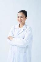 retrato de médico sorridente feliz em uniforme branco em pé com as mãos cruzadas sobre fundo branco foto