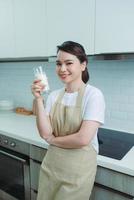 jovem feliz bebe um leite no café da manhã na cozinha conner. alimentação saudável e conceito de estilo de vida. foto