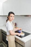 jovem mulher asiática atraente cozinha em uma cozinha, refogue foto