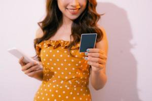 retrato de mulher loira sorridente pagando com cartão de crédito plástico no aplicativo para smartphone foto