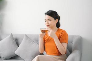 jovem relaxando em casa no sofá, ela está tomando um chá foto