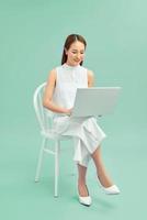 bela estudante sentada em uma cadeira com um laptop foto