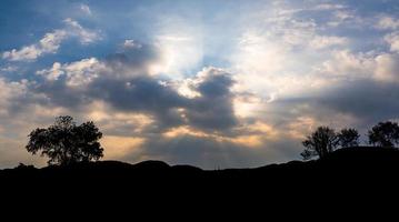 pôr do sol panorâmico com nuvens no céu crepuscular com silhueta de montanha foto