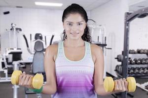 mulher levantando dois halteres no centro de fitness foto