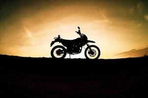 turista motocicleta motocross silhueta parque na montanha à noite. conceito de viagem de aventura foto