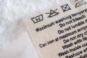 etiqueta de roupas de instruções de lavagem de cuidados com a roupa no fundo de textura de tecido foto