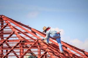 trabalhadores de solda instalando estrutura de armação de aço do telhado da casa no canteiro de obras foto