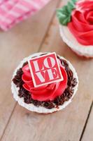 cupcakes de rosas vermelhas na mesa de madeira foto