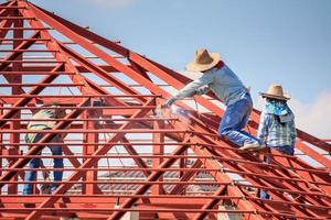 trabalhadores de solda instalando estrutura de armação de aço do telhado da casa no canteiro de obras foto