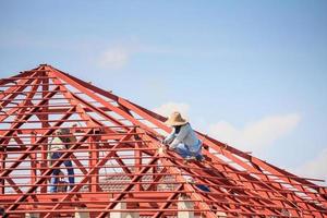 trabalhadores de solda instalando estrutura de armação de aço do telhado da casa no canteiro de obras foto