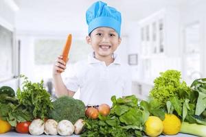 menino feliz chef com legumes frescos foto