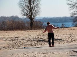 dnepr, ucrânia - 21.02.2022, um homem de meia idade faz ginástica na margem do rio. o conceito de um estilo de vida saudável e a luta contra o peso da linha. foto