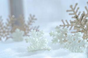 natal do inverno - flocos de neve de natal na neve, conceito de férias de inverno. decorações de flocos de neve brancos e dourados em fundo de neve foto