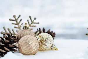 natal de inverno - bolas de natal com fita na neve, conceito de férias de inverno. bolas vermelhas de natal, bolas douradas, decorações de pinho e flocos de neve em fundo de neve foto