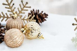 natal de inverno - bolas de natal com fita na neve, conceito de férias de inverno. bolas vermelhas de natal, bolas douradas, decorações de pinho e flocos de neve em fundo de neve foto