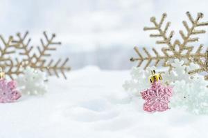 natal do inverno - flocos de neve de natal na neve, conceito de férias de inverno. decorações de flocos de neve brancos e dourados em fundo de neve foto