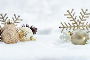 natal de inverno - bolas de natal com fita na neve, conceito de férias de inverno. bolas vermelhas de natal, bolas douradas, decorações de pinho e flocos de neve em fundo de neve foto