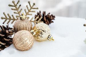 natal de inverno - bolas de natal com fita na neve, conceito de férias de inverno. bolas vermelhas de natal, bolas douradas, decorações de pinho e flocos de neve em fundo de neve foto