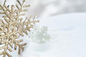 natal de inverno - bolas de natal com fita na neve, conceito de férias de inverno. bolas vermelhas de natal, bolas douradas, decorações de pinho e flocos de neve em fundo de neve foto