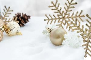 natal de inverno - bolas de natal com fita na neve, conceito de férias de inverno. bolas vermelhas de natal, bolas douradas, decorações de pinho e flocos de neve em fundo de neve foto