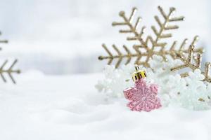 natal de inverno - bolas de natal com fita na neve, conceito de férias de inverno. bolas vermelhas de natal, bolas douradas, decorações de pinho e flocos de neve em fundo de neve foto