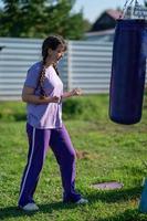 menina socando o saco de areia. treinamento de boxe muaythai. garota saudável socando no saco de boxe. conceito de treinamento de boxe, exercício, malhando em fitness, esporte foto