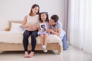 uma família asiática, pais e filhas estão assistindo a um filme de ultra-som de uma criança no ventre de sua mãe foto