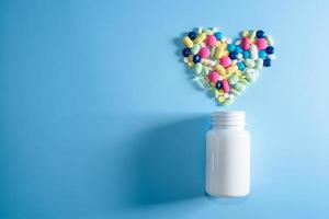 pílulas, comprimidos e cápsulas de medicamentos farmacêuticos variados para o tratamento de doenças cardíacas. forma de coração e frasco de comprimidos. copie o espaço para o texto foto