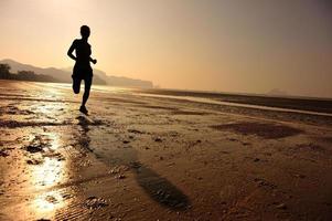 mulher jovem fitness correndo na praia do nascer do sol foto