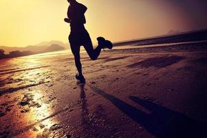 mulher jovem fitness correndo na praia do nascer do sol foto