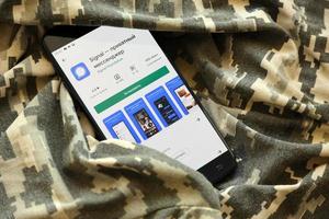 ternopil, ucrânia - 24 de abril de 2022 sinalizar a página da loja de aplicativos de mensagens privadas na exibição de um smartphone móvel preto na camuflagem militar ucraniana foto