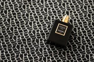 ternopil, ucrânia - 2 de setembro de 2022 coco noir chanel paris mundialmente famoso frasco de perfume francês na velha manta com padrão monocromático foto